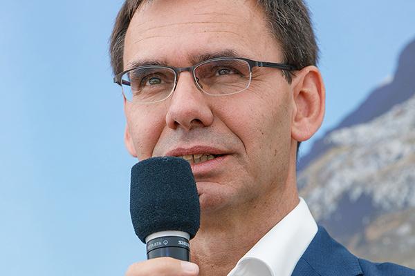 Landeshauptmann Wallner mit Mikrofon redend vor Bergkulisse